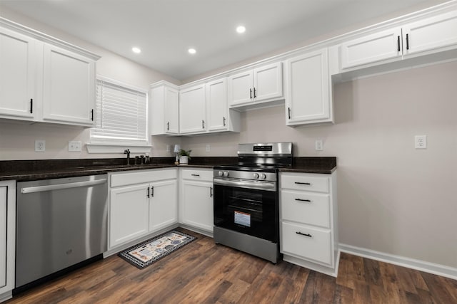 kitchen featuring sink, appliances with stainless steel finishes, dark stone countertops, white cabinets, and dark hardwood / wood-style flooring