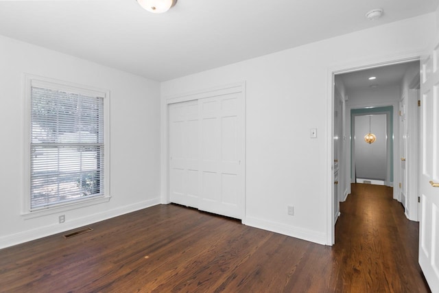 unfurnished bedroom with a closet and dark hardwood / wood-style floors