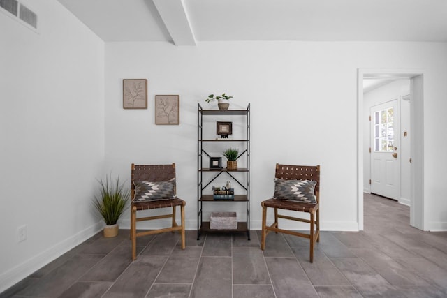 living area featuring beam ceiling and dark tile patterned flooring