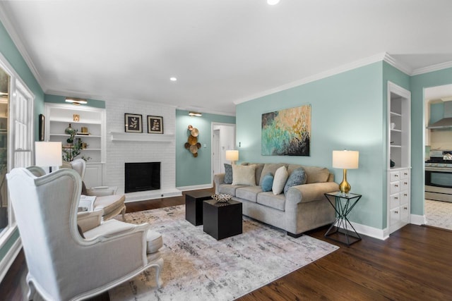 living room featuring dark hardwood / wood-style flooring, ornamental molding, a fireplace, and built in features