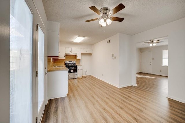 kitchen with a textured ceiling, light hardwood / wood-style floors, stainless steel range with gas stovetop, and white cabinets