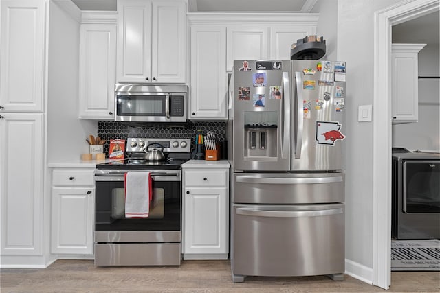 kitchen with stainless steel appliances, white cabinetry, light hardwood / wood-style flooring, and washer / clothes dryer