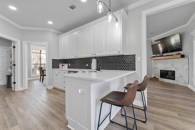 kitchen featuring sink, decorative light fixtures, light hardwood / wood-style floors, and white cabinets