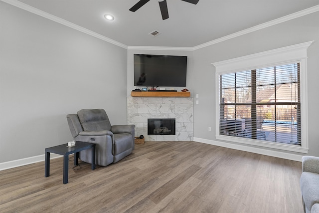 sitting room with crown molding, a fireplace, ceiling fan, and hardwood / wood-style flooring