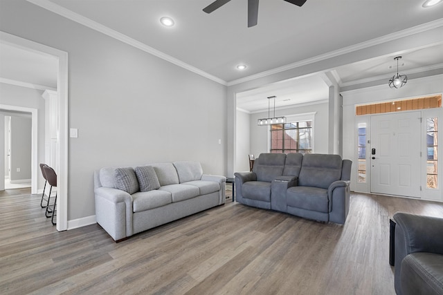 living room featuring hardwood / wood-style floors, crown molding, and ceiling fan with notable chandelier