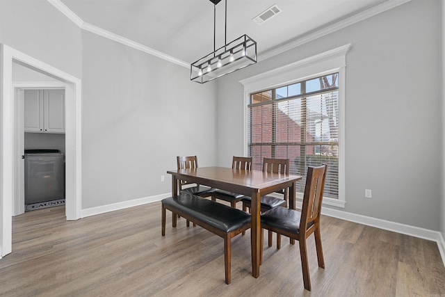 dining area featuring crown molding, light hardwood / wood-style floors, and a chandelier