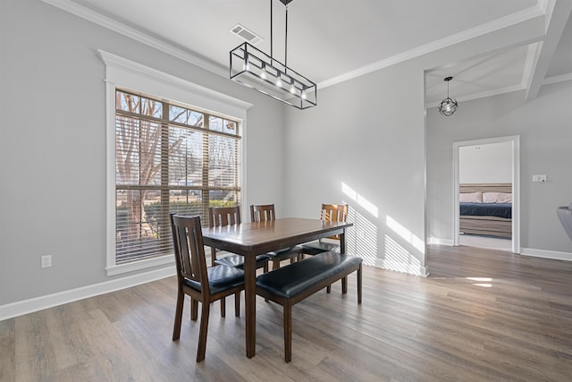 dining area with hardwood / wood-style flooring, crown molding, and a chandelier