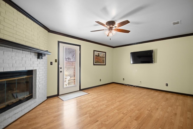 unfurnished living room with a brick fireplace, crown molding, light hardwood / wood-style floors, and ceiling fan