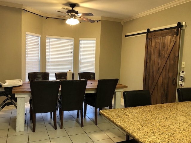 dining space featuring crown molding, a barn door, light tile patterned floors, and ceiling fan