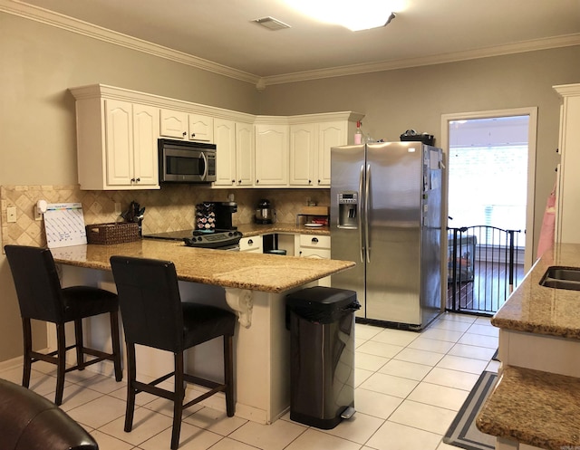 kitchen with white cabinetry, a breakfast bar area, stainless steel appliances, and kitchen peninsula