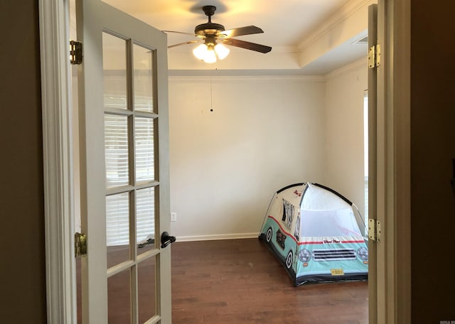 unfurnished bedroom with a tray ceiling, crown molding, dark wood-type flooring, and ceiling fan