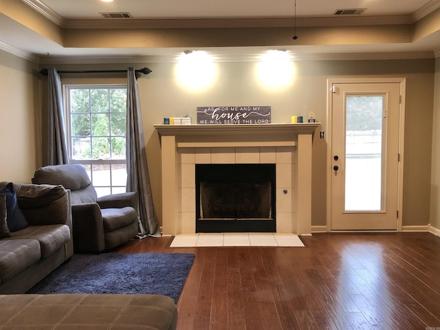 living room with hardwood / wood-style floors, a tray ceiling, a fireplace, and ornamental molding