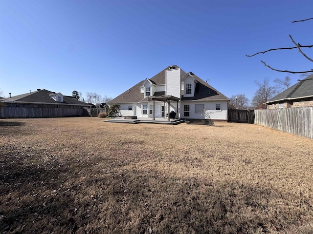 back of property with a wooden deck and a lawn