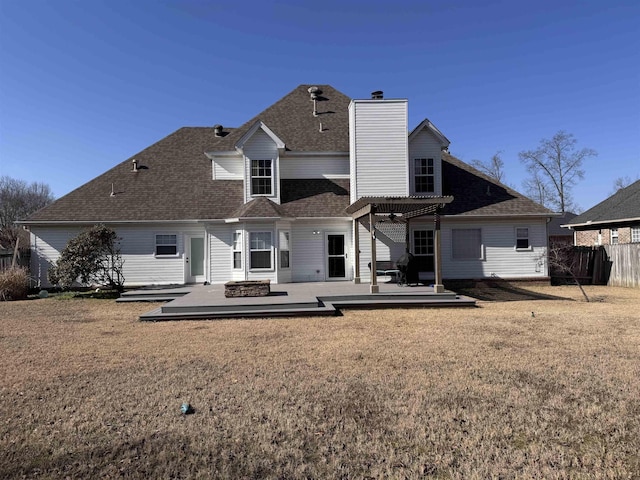 back of property with a wooden deck, an outdoor fire pit, a yard, and a pergola