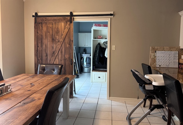 tiled dining room with a barn door and washer / dryer