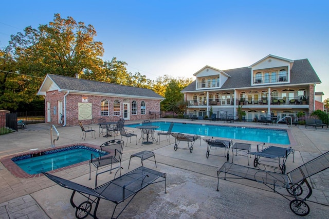 view of pool with a community hot tub, an outdoor structure, and a patio