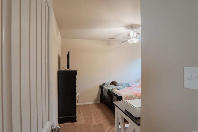 bedroom featuring a textured ceiling, light colored carpet, and ceiling fan