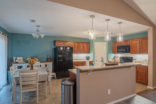 kitchen with pendant lighting, a kitchen breakfast bar, black appliances, an island with sink, and decorative backsplash