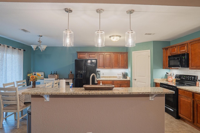 kitchen featuring a kitchen island with sink, a breakfast bar area, and black appliances