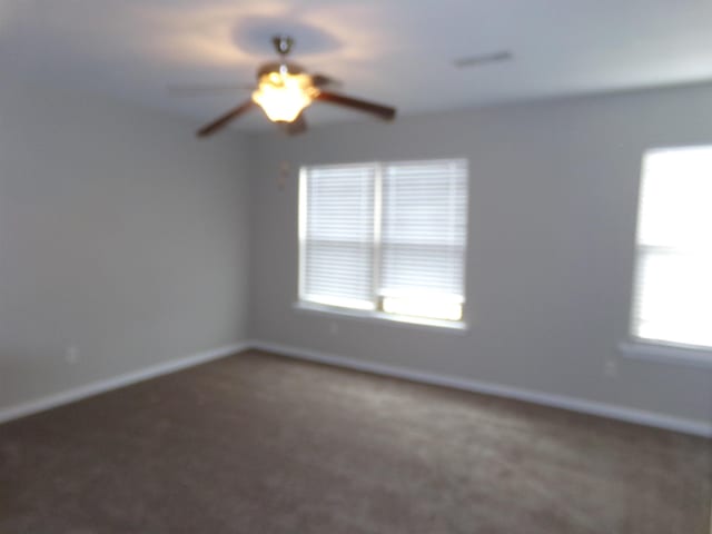 unfurnished room featuring ceiling fan and dark carpet