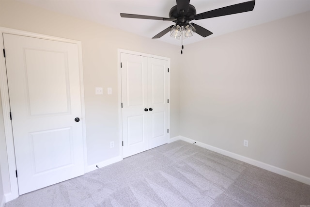 unfurnished bedroom with light colored carpet, ceiling fan, and a closet