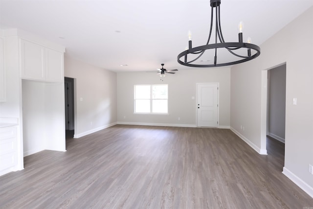 unfurnished living room featuring ceiling fan with notable chandelier and hardwood / wood-style floors