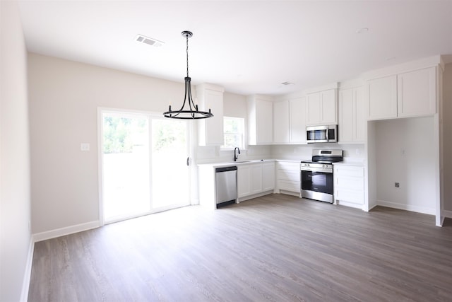 kitchen featuring sink, hardwood / wood-style flooring, appliances with stainless steel finishes, white cabinetry, and hanging light fixtures