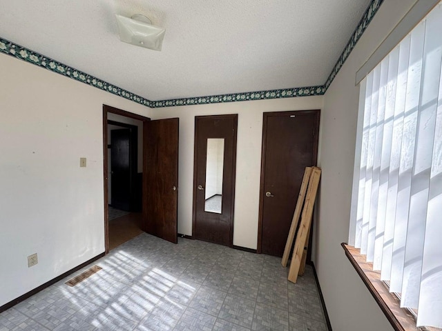 unfurnished bedroom with a textured ceiling and multiple closets