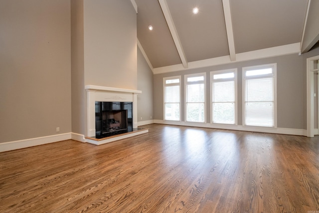 unfurnished living room with beam ceiling, hardwood / wood-style floors, and high vaulted ceiling