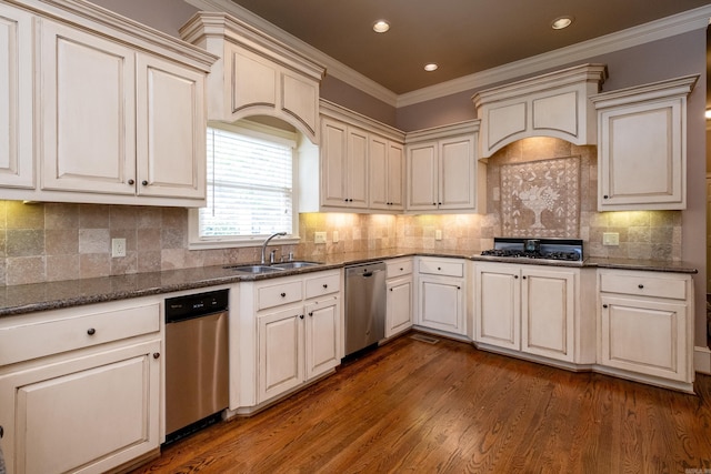 kitchen with dark wood-type flooring, sink, dark stone countertops, ornamental molding, and appliances with stainless steel finishes