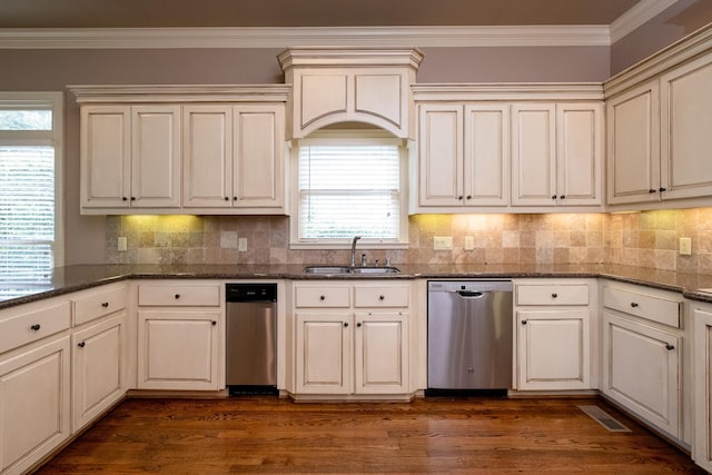 kitchen with sink, dark stone countertops, dark hardwood / wood-style flooring, ornamental molding, and stainless steel dishwasher