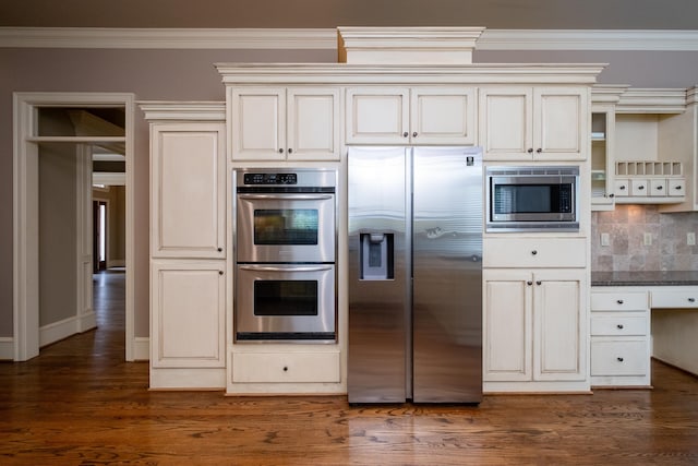 kitchen with appliances with stainless steel finishes, dark stone countertops, backsplash, ornamental molding, and dark hardwood / wood-style flooring