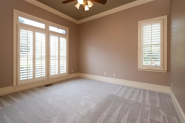 carpeted spare room with ornamental molding, a wealth of natural light, and ceiling fan