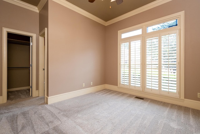 unfurnished bedroom featuring a walk in closet, ornamental molding, a closet, and carpet