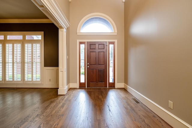 foyer entrance featuring a towering ceiling and dark hardwood / wood-style floors