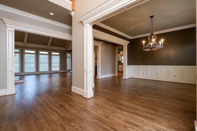 unfurnished room with ornate columns, ornamental molding, dark hardwood / wood-style floors, and an inviting chandelier