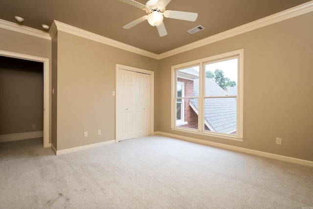 unfurnished bedroom with ornamental molding, light carpet, ceiling fan, and a closet