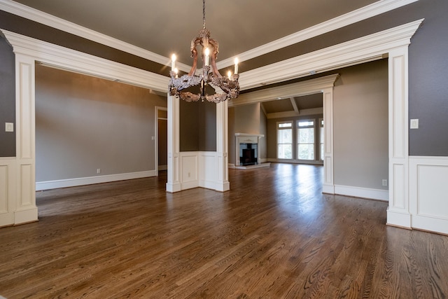 unfurnished living room featuring a notable chandelier, crown molding, and dark hardwood / wood-style floors