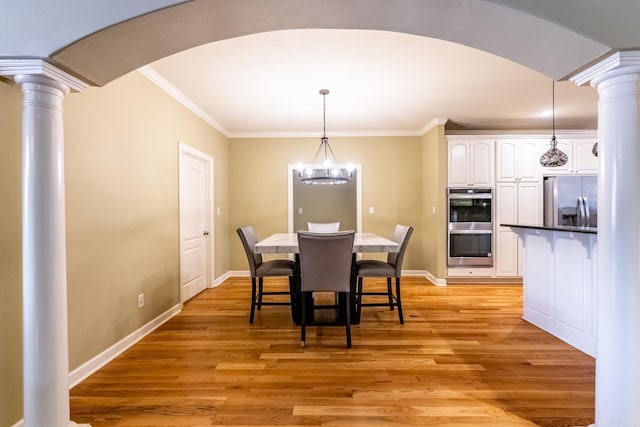 dining space featuring ornate columns, ornamental molding, an inviting chandelier, and light hardwood / wood-style floors