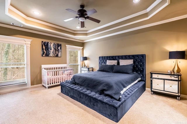 carpeted bedroom with crown molding, a tray ceiling, and ceiling fan