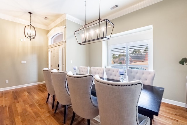 dining room with an inviting chandelier, ornamental molding, and light hardwood / wood-style flooring