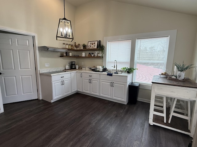 kitchen featuring lofted ceiling, sink, white cabinetry, hanging light fixtures, and dark hardwood / wood-style floors