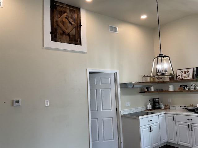 kitchen featuring black electric cooktop, hanging light fixtures, and white cabinets