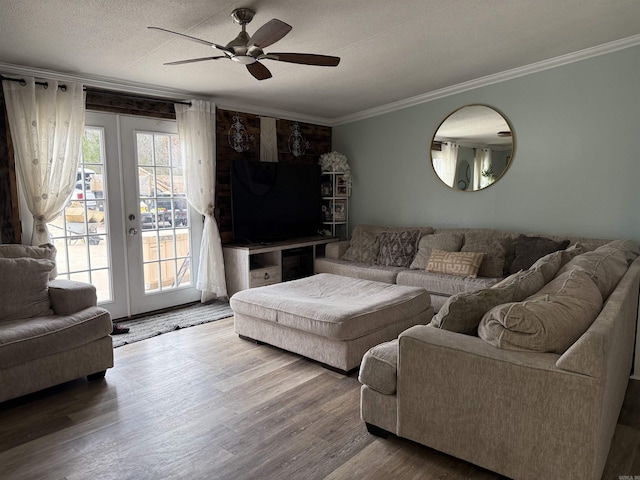 living room with wood-type flooring, ceiling fan, crown molding, a textured ceiling, and french doors