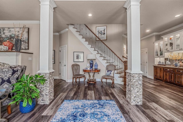 foyer with dark hardwood / wood-style flooring, crown molding, and decorative columns