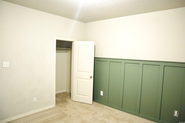 unfurnished bedroom featuring light colored carpet and a closet