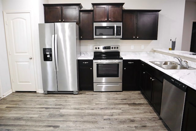 kitchen featuring dark brown cabinetry, sink, light wood-type flooring, and appliances with stainless steel finishes