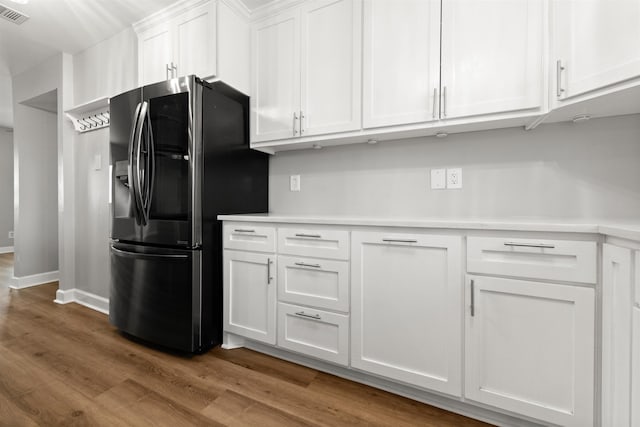 kitchen featuring white cabinetry, wood-type flooring, and stainless steel fridge