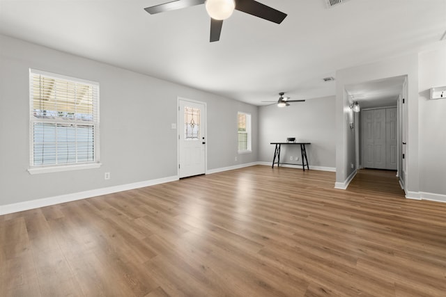 unfurnished living room with ceiling fan, wood-type flooring, and a healthy amount of sunlight