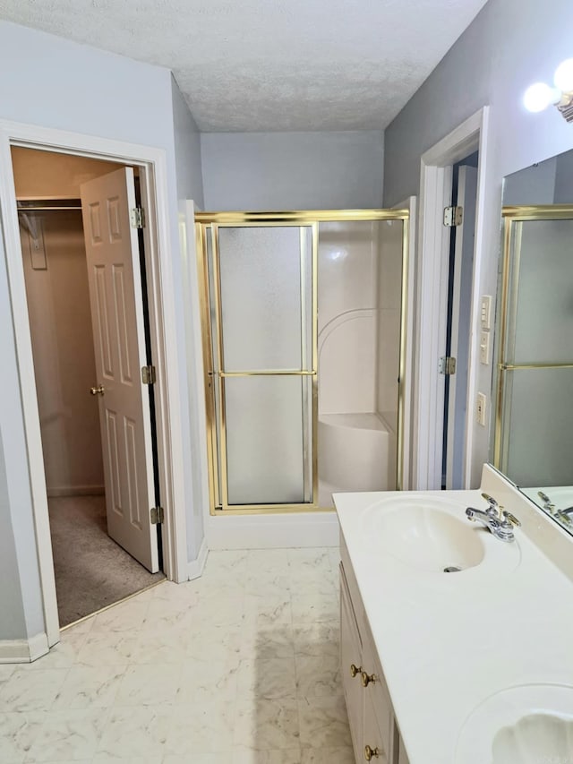 bathroom with vanity, an enclosed shower, and a textured ceiling